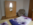 Schlafzimmer mit Laminatboden, helles Zimmer, Kleiderschrank mit Spiegel und Kleiderbügeln, bequemer Sessel und Bett